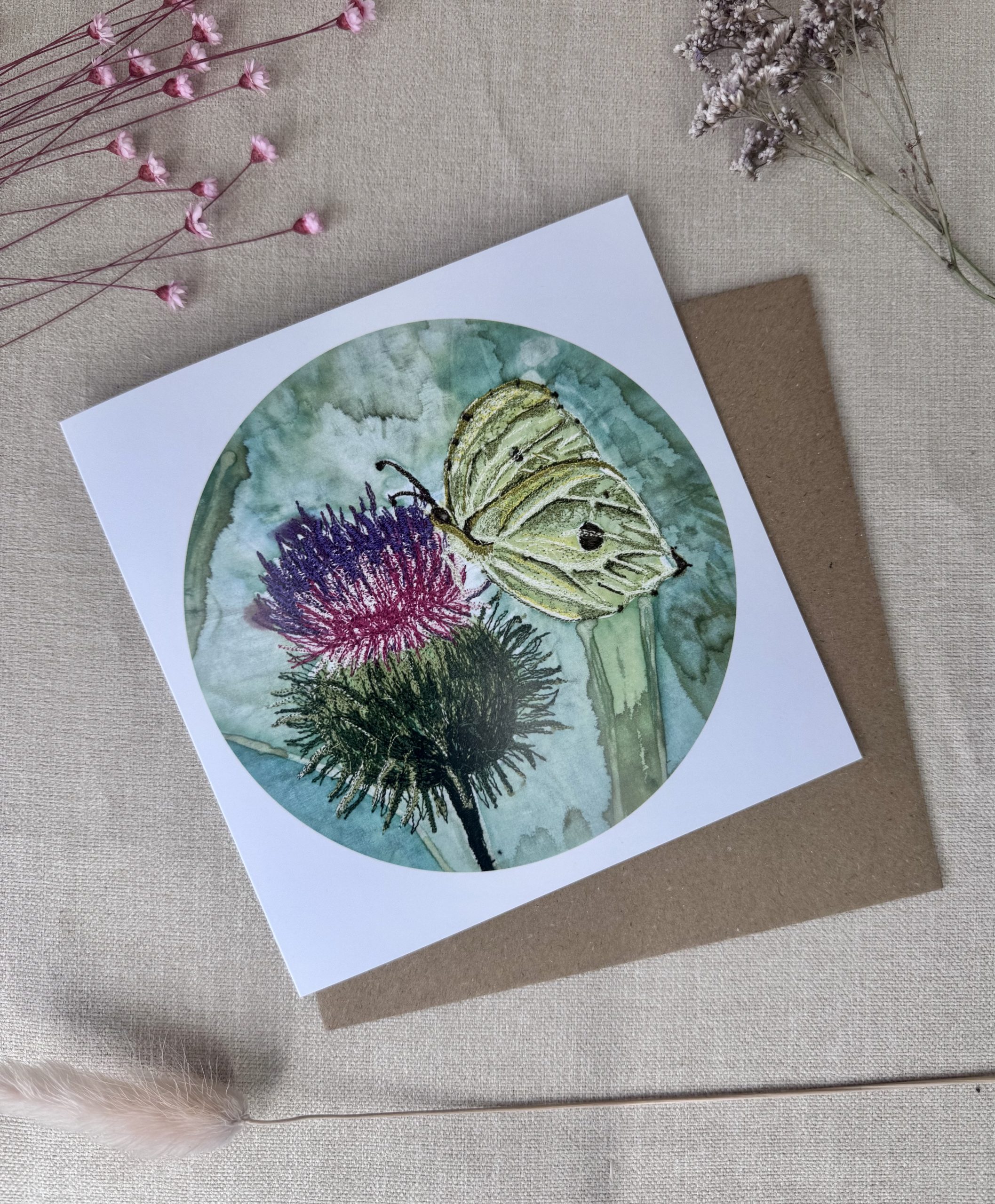 A printed card featuring an original hand-painted embroidered Brimstone Butterfly artwork resting on a thistle.