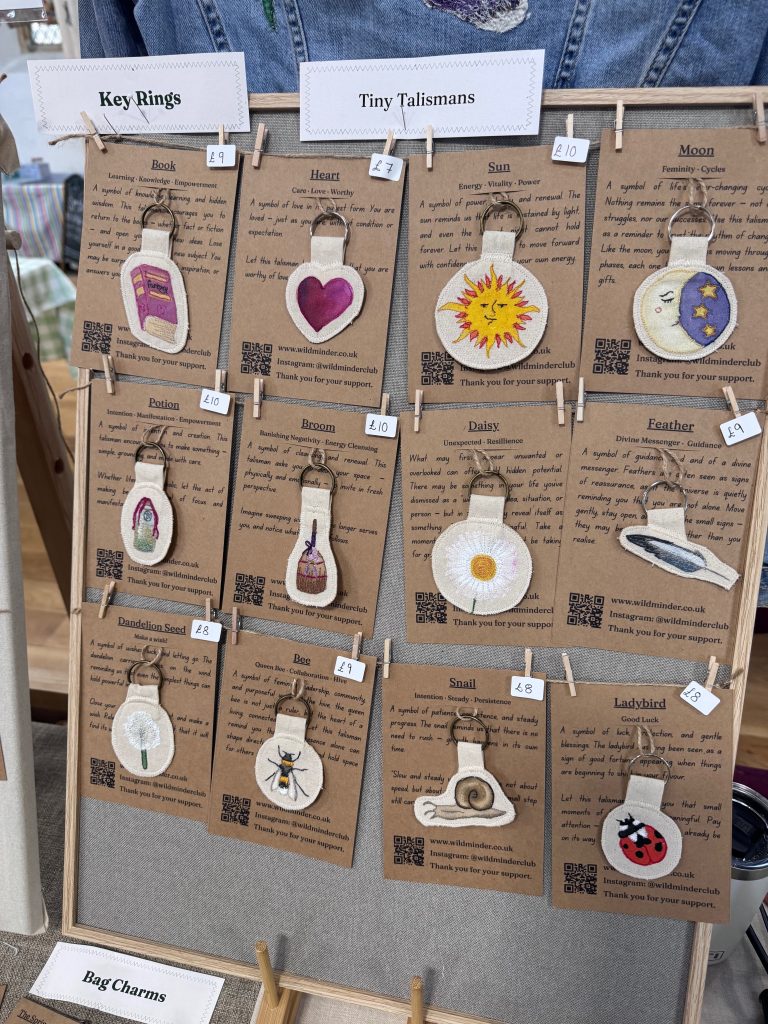 A photo showing the display of the Wild Minder tiny talismans - Key Rings on backed cardboard cards hung up with wooden pegs.