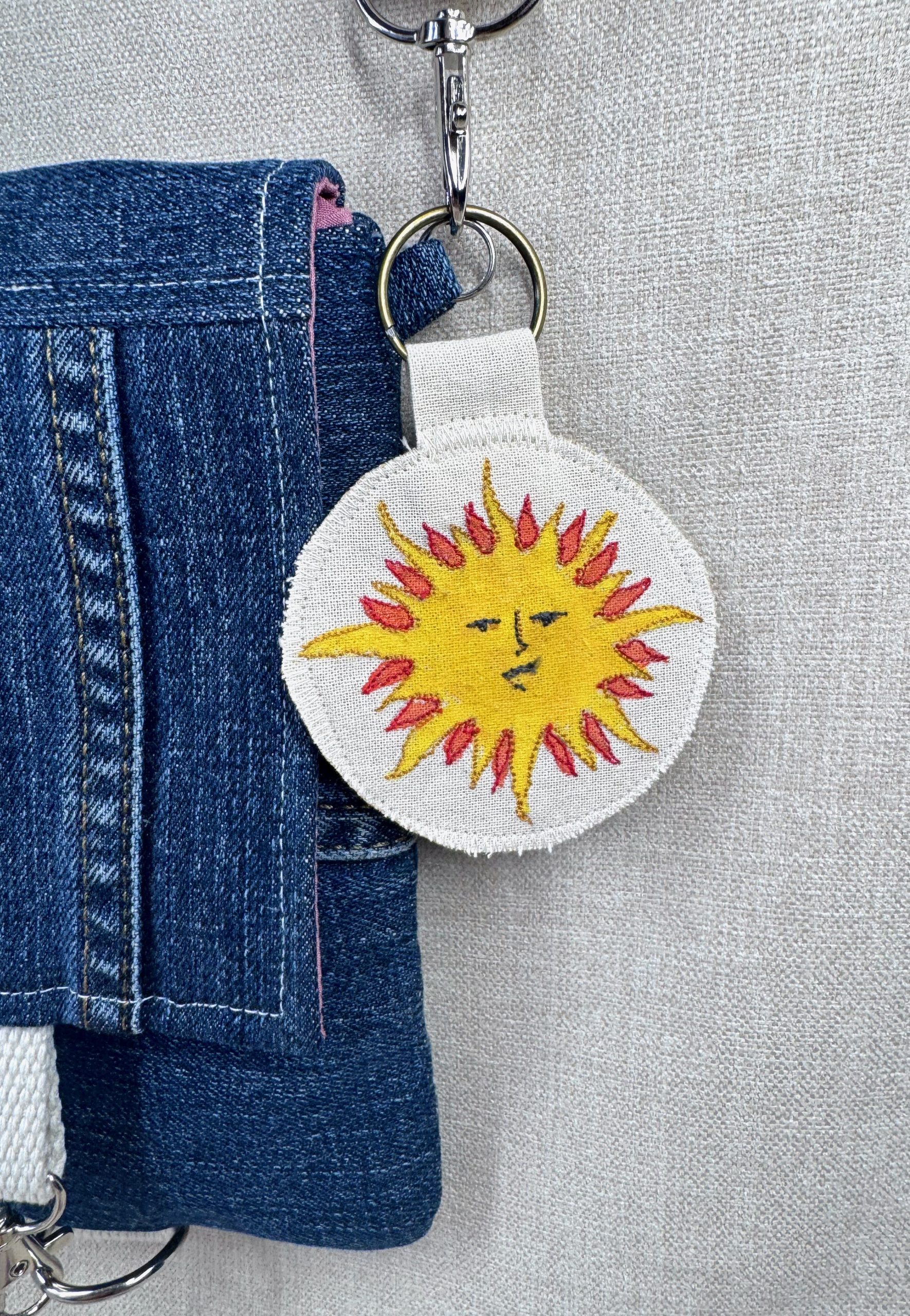 A photo of the Wild Minder Sun Talisman Keyring clipped on to a Wild Minder Scrappy Bag